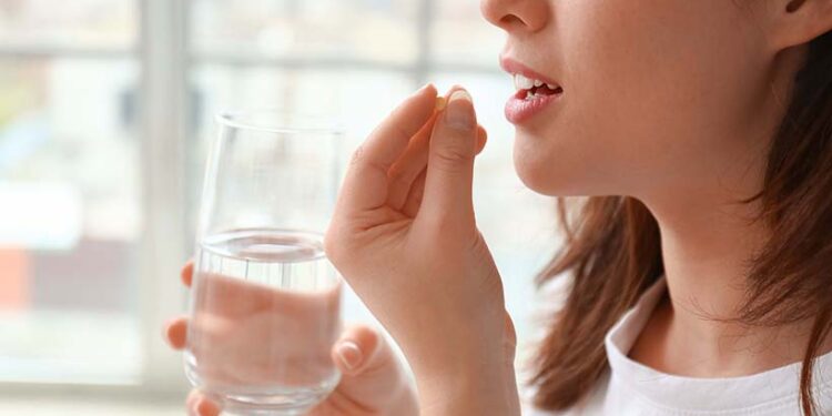 Young woman taking pills at home